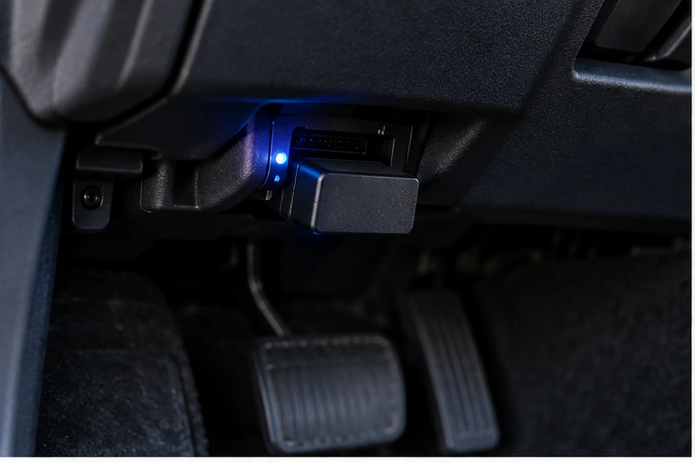 A blue-lit OBD2 adapter plugged under a car dashboard, illustrating how a connected device can keep the vehicle CAN bus active.