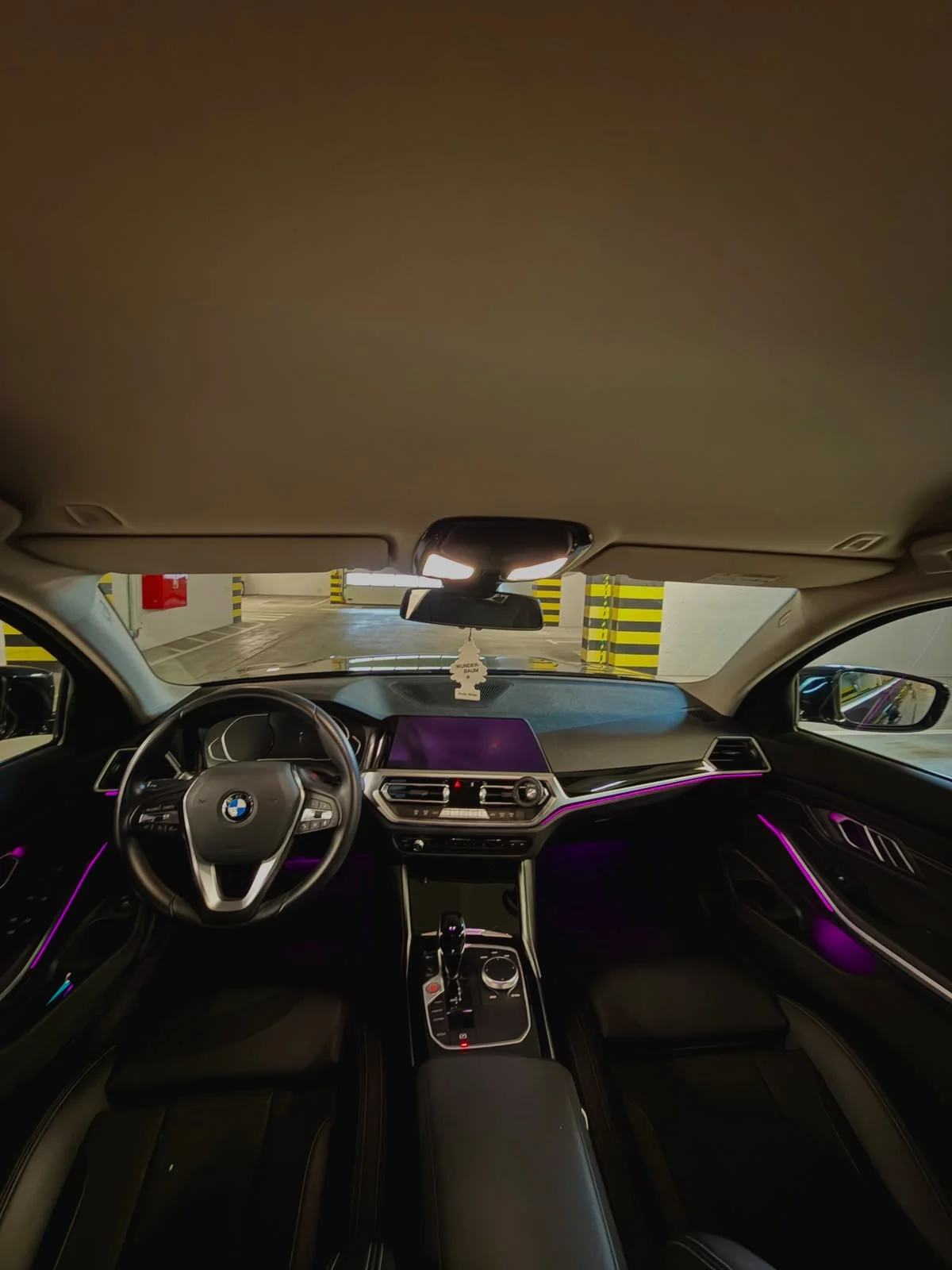 Interior of Kamil’s BMW with black leather seats, digital dashboard, and purple ambient lighting