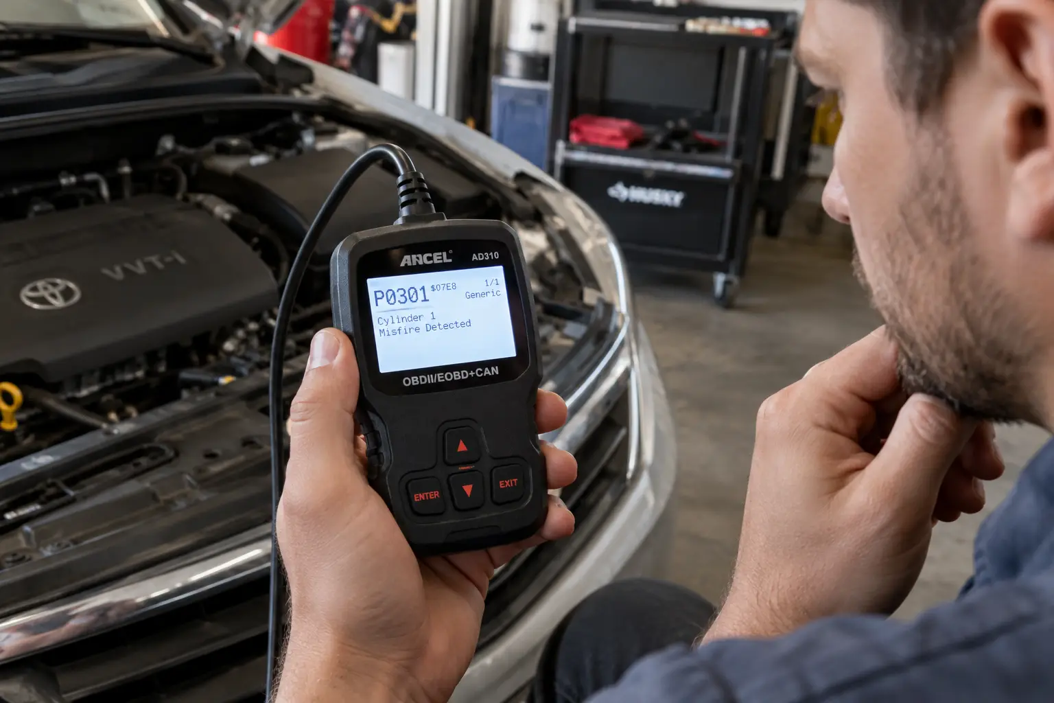 A man reading a P0301 cylinder misfire code on a handheld OBD2 scanner beside an open engine bay.